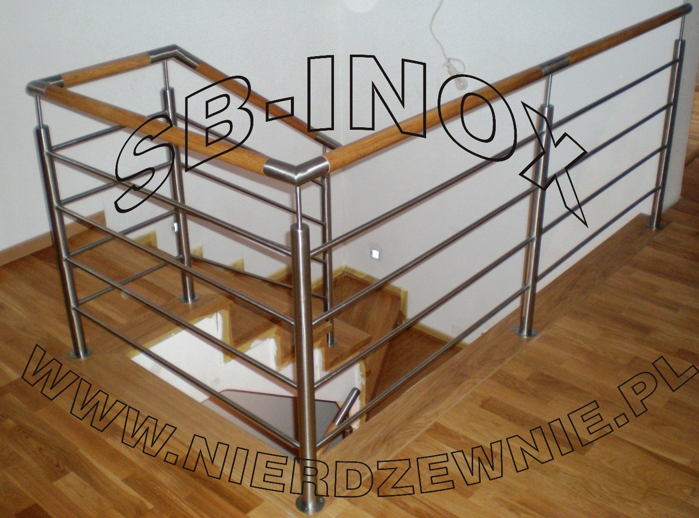 Schody z drewnianymi stopniami i balustradą ze stali nierdzewnej z drewnianą poręczą, widoczne z góry, z podświetleniem LED w ścianie.